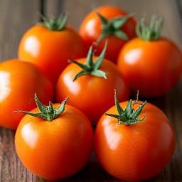 Fresh bush tomatoes displayed on a wooden surface, bright orange native fruit